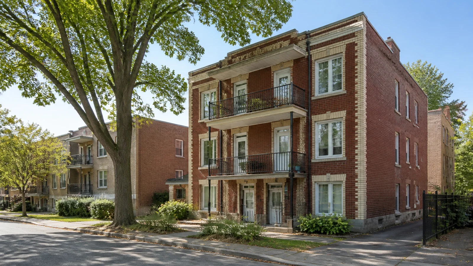 Triplex en brique avec balcons dans une rue résidentielle du Mercier–Hochelaga-Maisonneuve.
