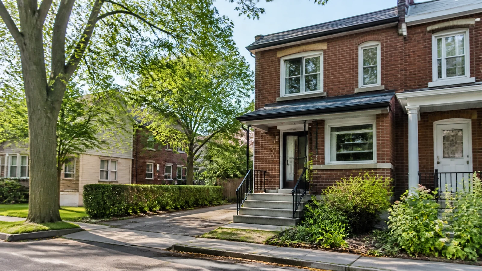 Maison de ville en brique avec jardin dans une rue arborée du Mercier–Hochelaga-Maisonneuve.