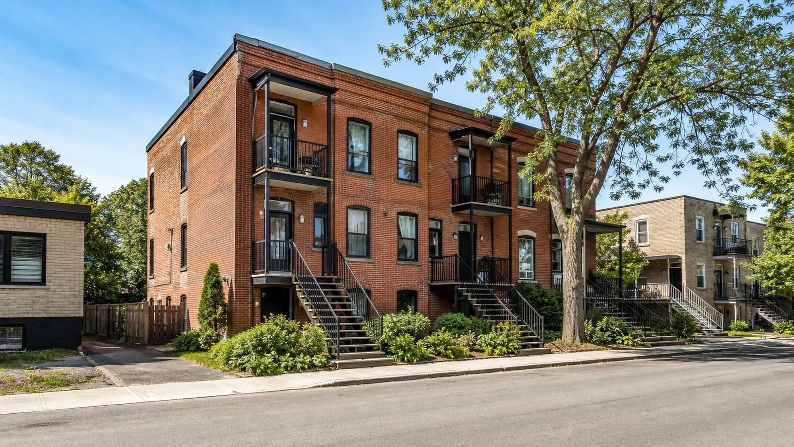 Triplex en brique avec balcons dans une rue résidentielle de Ville-Marie.